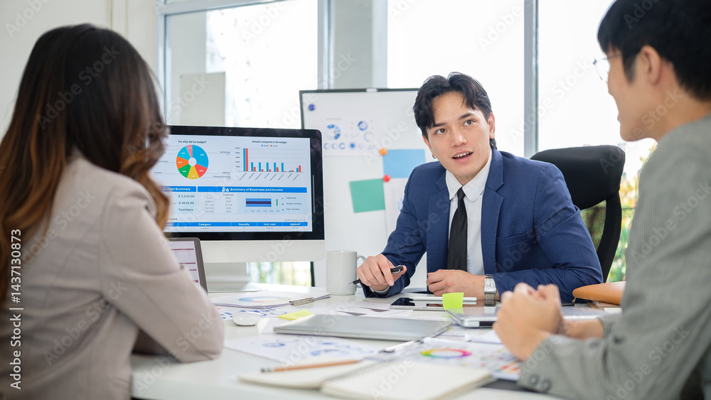 Confident male executive presenting ideas to coworkers during a collaborative meeting with visual financial summaries on display. Confident male executive presenting ideas to coworkers during a collaborative meeting with visual financial summaries on display.