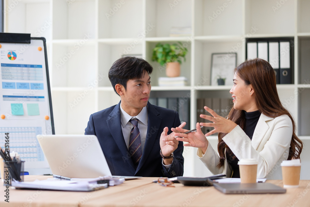 Confident professionals in formal attire discussing business strategies at a modern desk, surrounded by documents, coffee cups, and laptops. Confident professionals in formal attire discussing business strategies at a modern desk, surrounded by documents, coffee cups, and laptops.