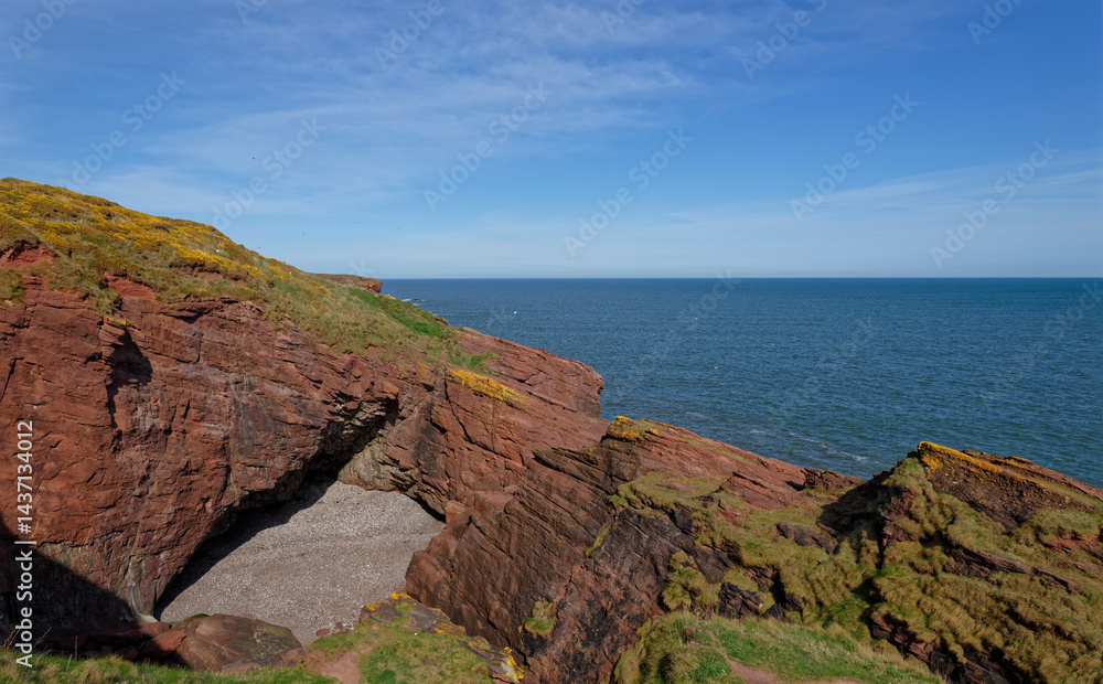 Obraz premium The small Shingle Beach at the Mermaids Kirk on the Arbroath Coastal Walk, the remnants of a large sea cave which has bowed formed a small Cove.