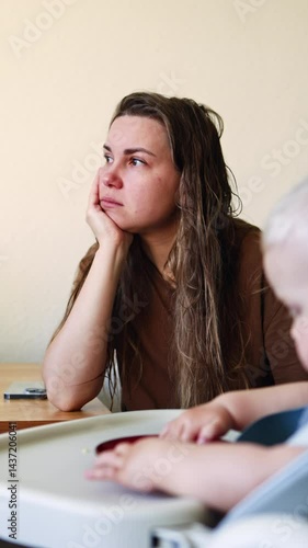 Sad woman sitting next to child and not paying attention to her. Depression on maternity leave. Mom has headache.