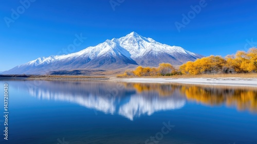 Serene mountain lake reflected in a calm water surface, with autumnal colors and snow-capped peak