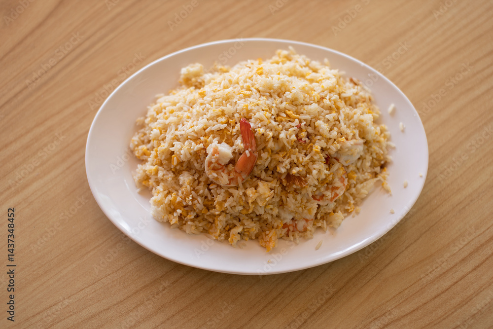 Shrimp fried rice in a white plate placed on a wooden table. Shrimp fried rice in a white plate placed on a wooden table.