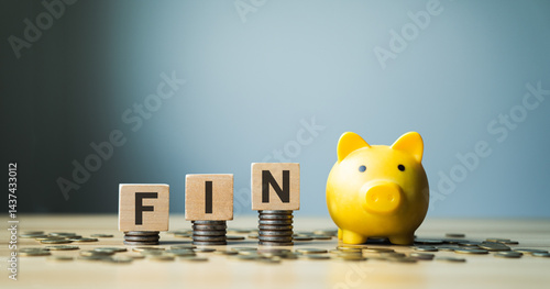 Fotografie FIN abbreviation with wooden blocks on stacked coins, yellow piggy bank, and sca