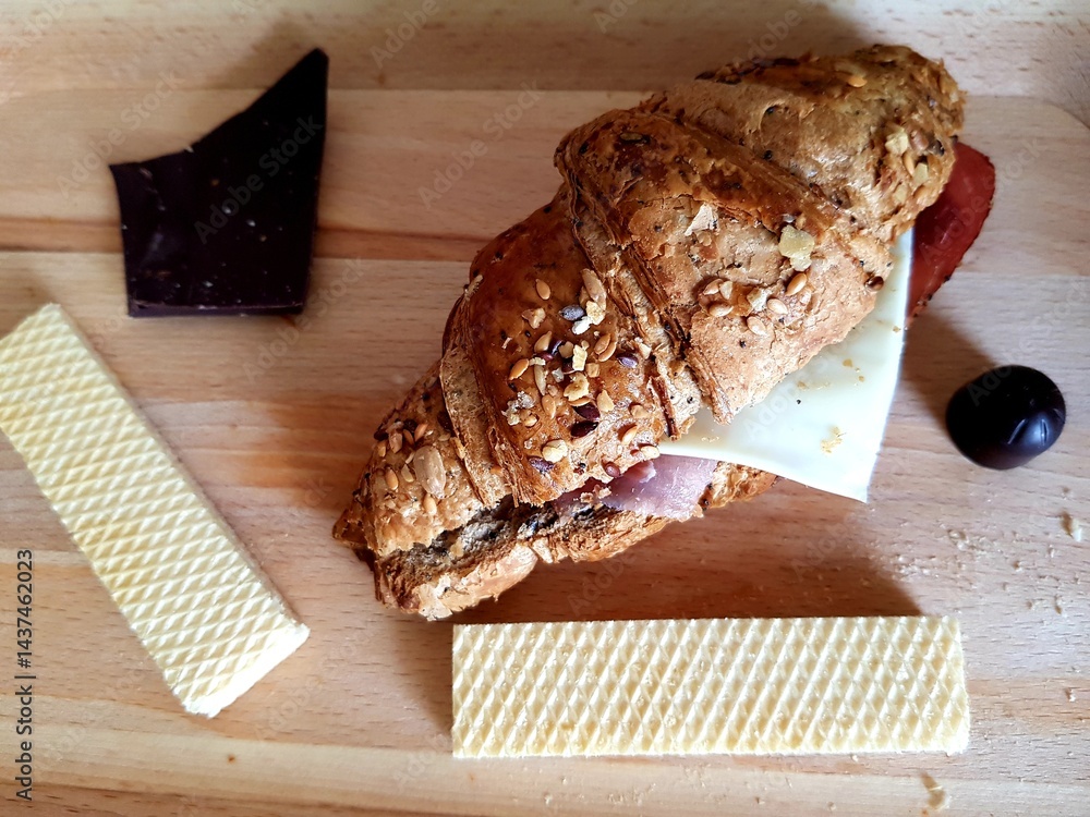 Croissant sandwich with cheese, ham, tomato and black olives