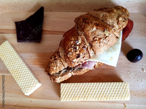 Obraz na płótnie Croissant sandwich with cheese, ham, tomato and black olives w salonie