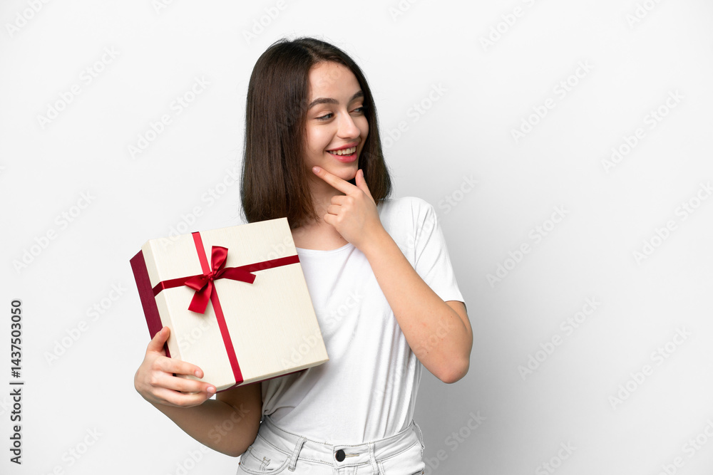 Young Ukrainian woman holding a gift isolated on white background thinking an idea and looking side Young Ukrainian woman holding a gift isolated on white background thinking an idea and looking side