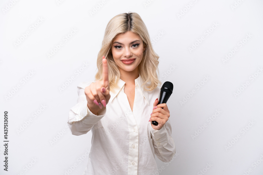 Young singer woman picking up a microphone isolated on white background showing and lifting a finger Young singer woman picking up a microphone isolated on white background showing and lifting a finger