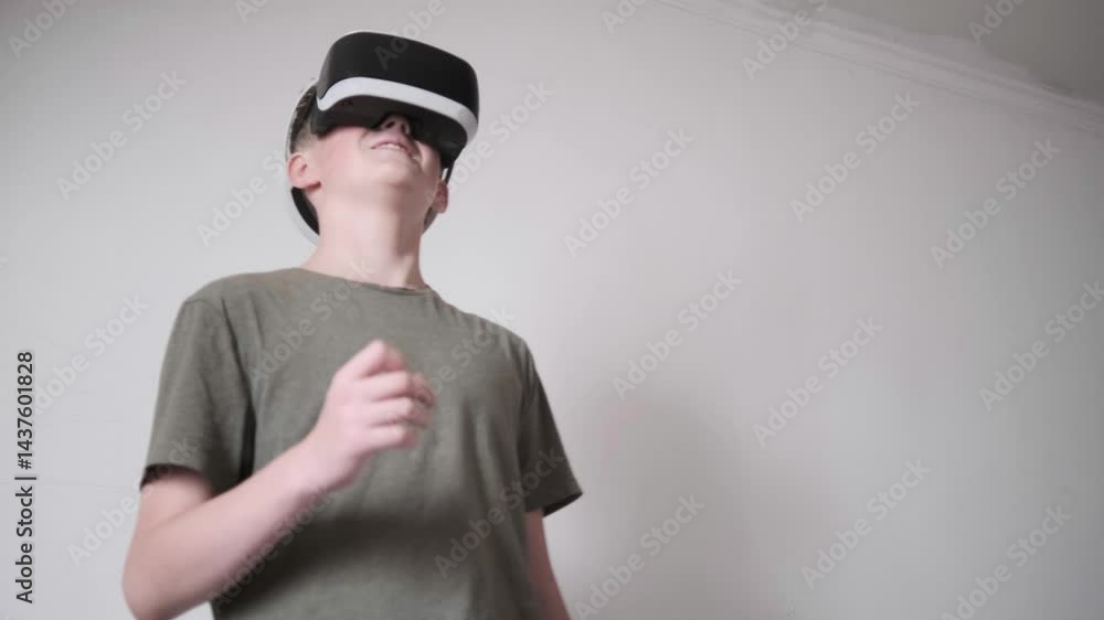 Teen boy standing in room, immersed in virtual reality headset game Teen boy standing in room, immersed in virtual reality headset game