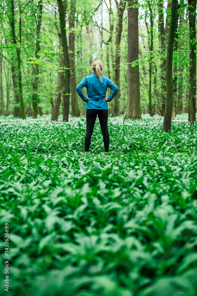 Woman athlete in sportswear standing confidently in forest, concept of fitness and healthy lifestyle