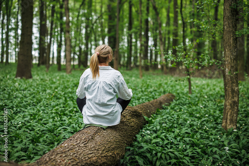 Obraz na płótnie Forest therapy. Woman sitting on tree trunk in spring woodland. Mindfulness and mental wellbeing in nature w salonie