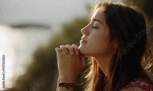 Woman in prayerful pose outdoors, serene and peaceful, by the sea, for meditation or mindfulness stock photo