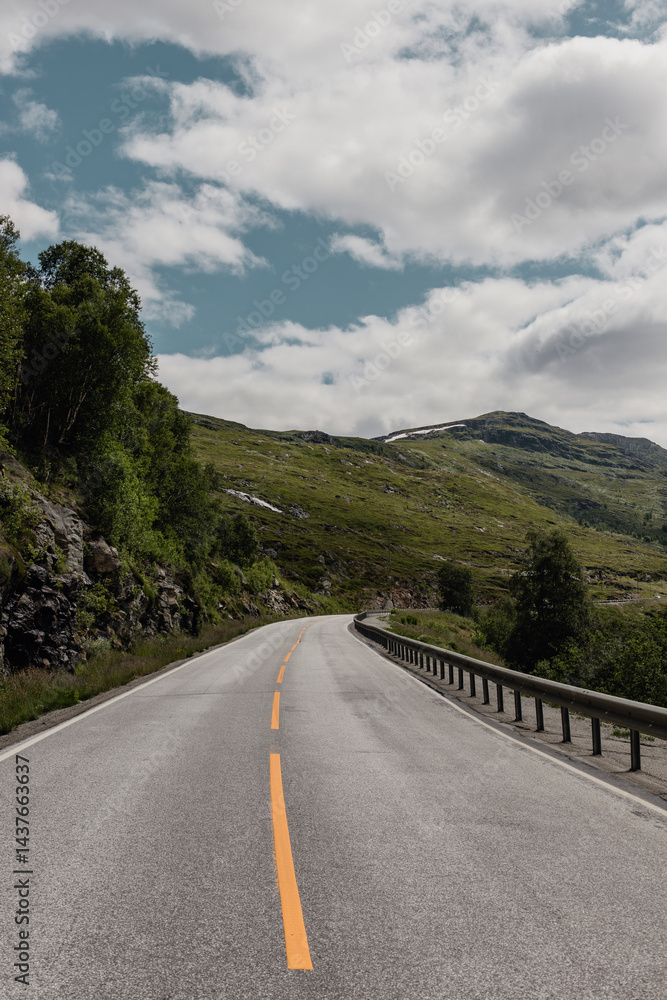 View from a car window onto a highway in Norway in a mountain valley where metal barriers have been installed for safety purposes View from a car window onto a highway in Norway in a mountain valley where metal barriers have been installed for safety purposes