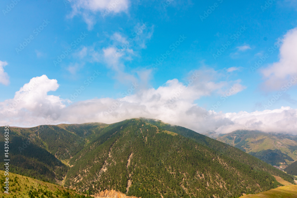Forest covered mountains with rolling clouds.