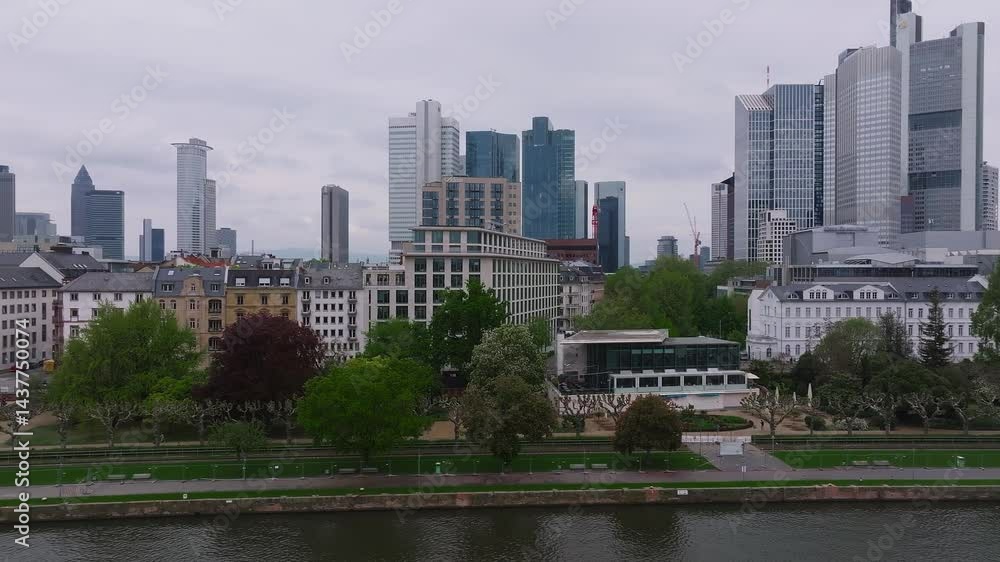 Aerial view of Frankfurt, Germany, featuring the skyline with Commerzbank Tower, the Main River with a cruising boat, and green riverbank trees. Aerial view of Frankfurt, Germany, featuring the skyline with Commerzbank Tower, the Main River with a cruising boat, and green riverbank trees.