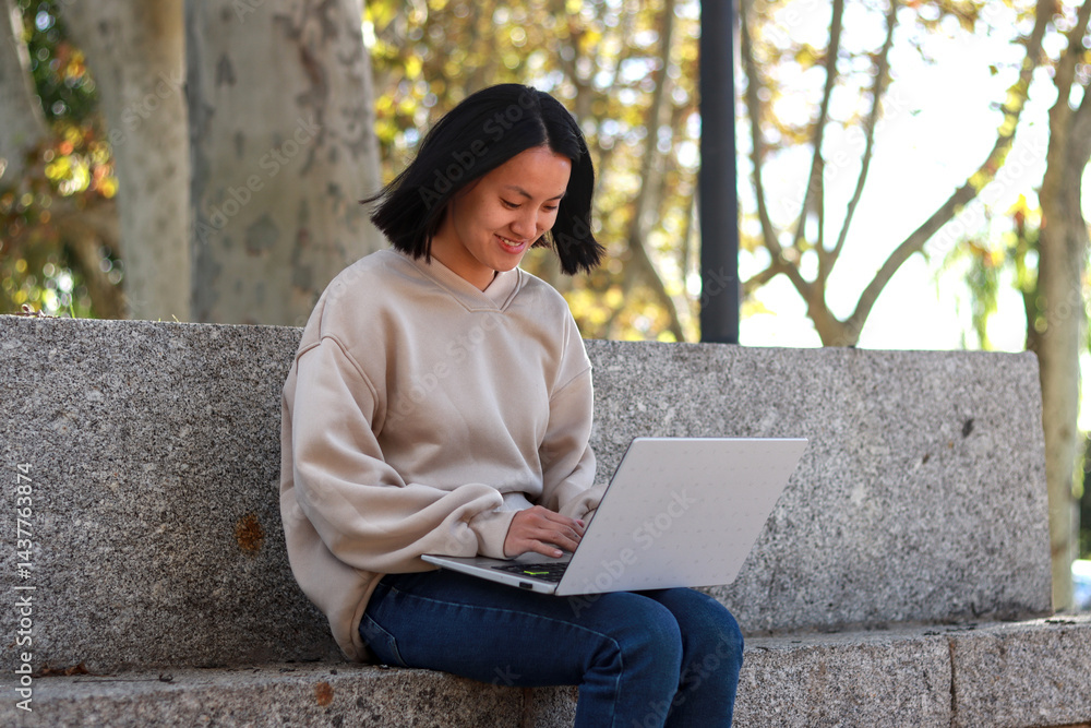 Young Asian woman sitting on outdoor stone steps, using a laptop Young Asian woman sitting on outdoor stone steps, using a laptop