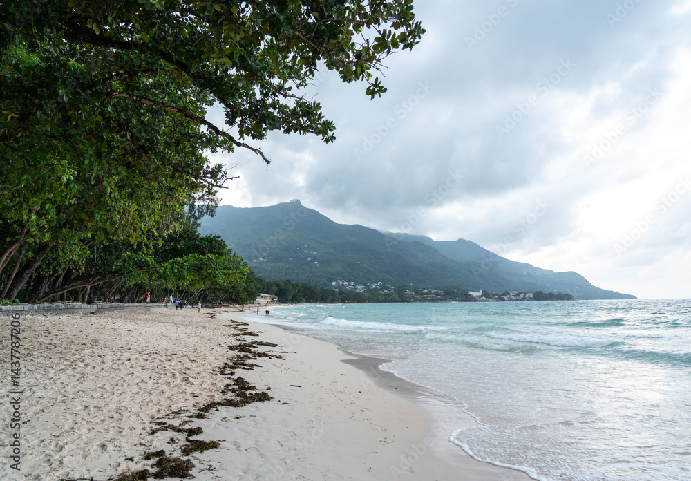 Anse Beau Vallon tropical beach in cloudy weather, ocean waves out of season on Mahe island