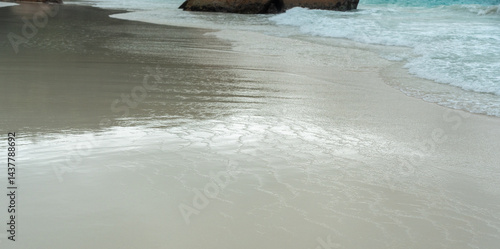 Obraz na płótnie Close view of wet sandy beach with gentle ocean waves and soft reflections, captured on Praslin w salonie