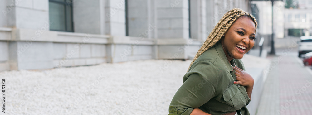 African american smiling woman looking back in the city streets. Joy, confidence, and positive emotions in an urban environment. Banner with copy space.