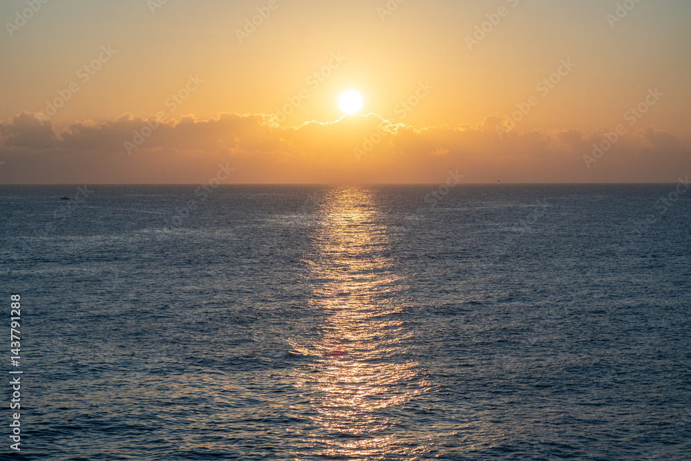 Sunset over the ocean, with the sun low on the horizon, contrast between sky and sea