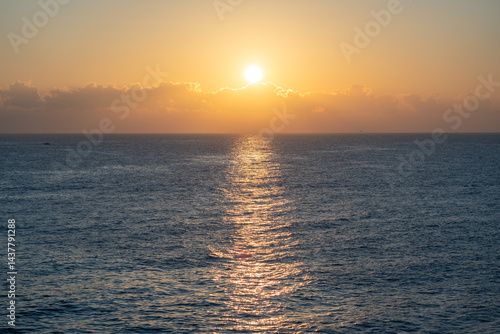 Obraz na płótnie Sunset over the ocean, with the sun low on the horizon, contrast between sky and sea w salonie