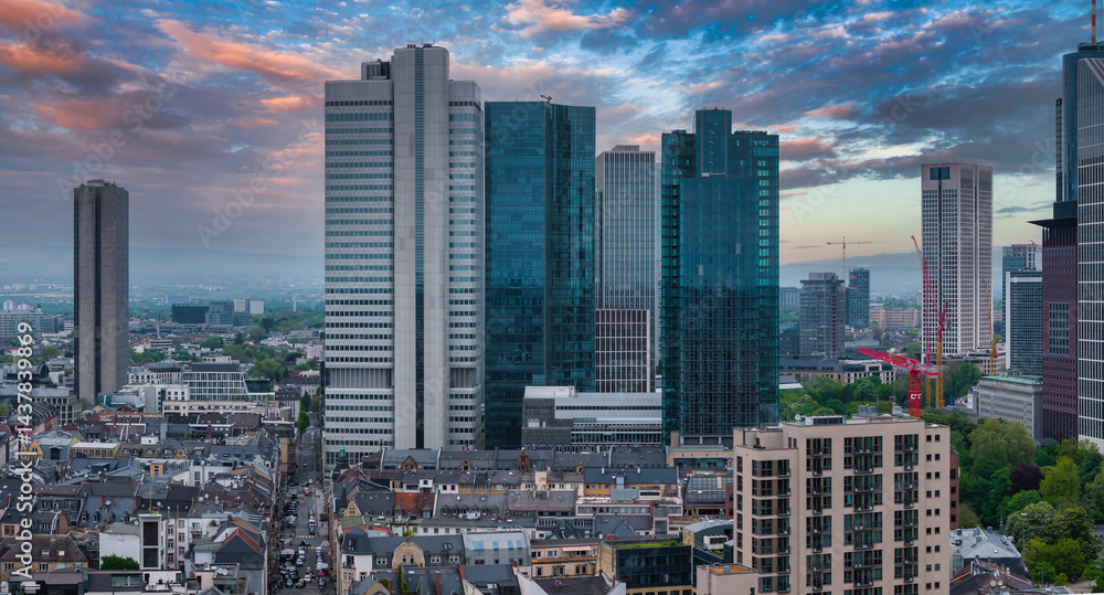 Aerial view of Frankfurt, Germany, showcasing the skyline with Eurotower, modern skyscrapers, traditional architecture, and a vibrant sunset sky.