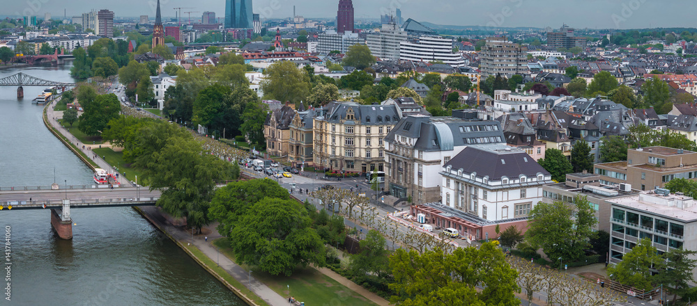 Aerial image of Frankfurt, Germany, featuring the Main River, a bridge, the European Central Bank, a Gothic church spire, and urban greenery.