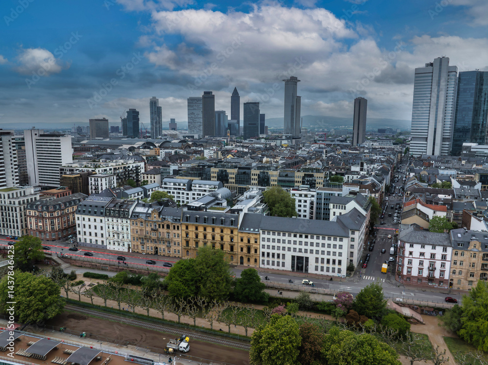 Aerial view of Frankfurt, Germany, featuring the Messeturm skyscraper, modern and historic architecture, tree lined streets, and a park area.