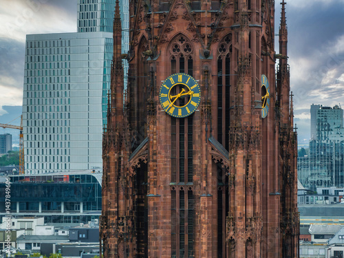 Obraz na płótnie The Frankfurt Cathedral's Gothic architecture and red sandstone tower stand out against modern skyscrapers under a cloudy sky in Frankfurt, Germany. w salonie