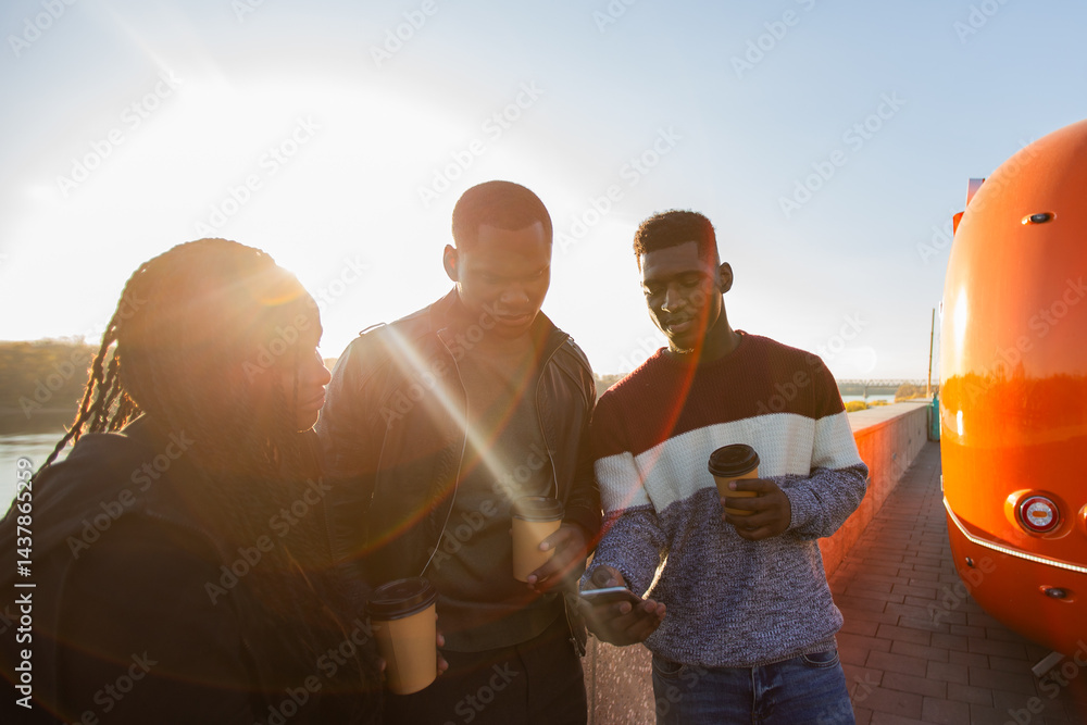 African american friends looking smartphone while standing by river. Concept of technology, friendship, real life connection.
