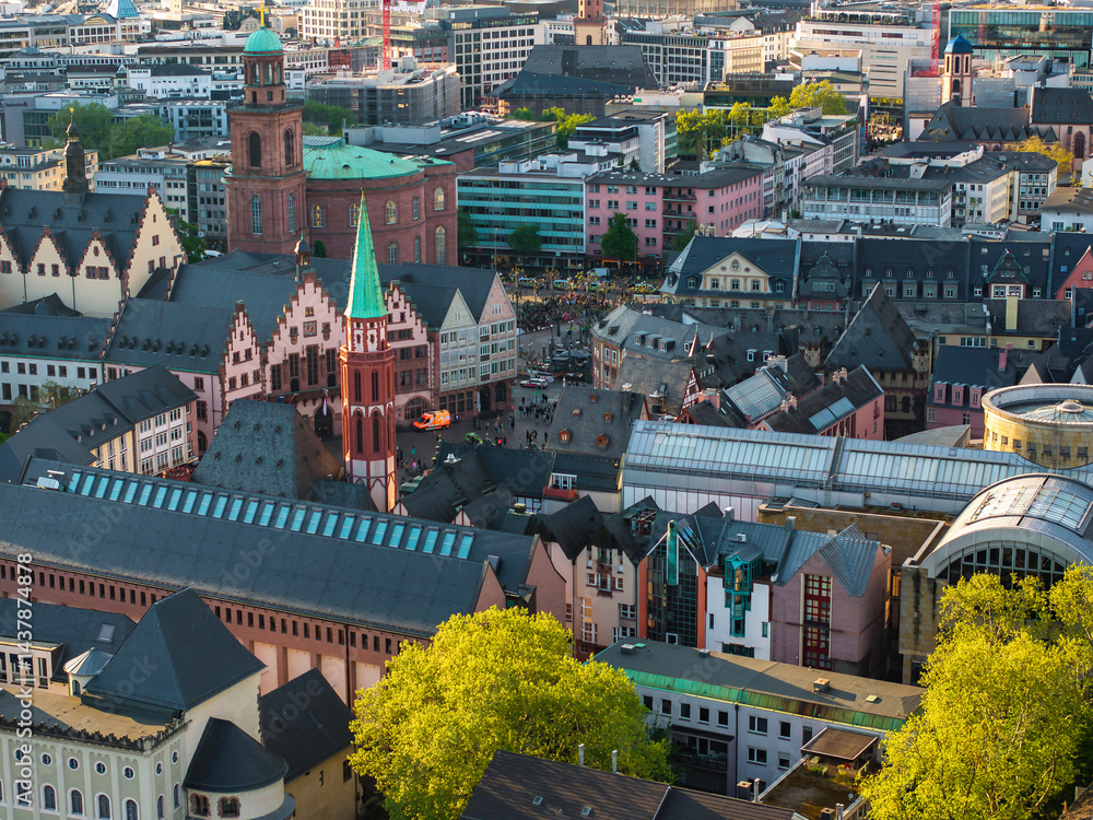 Aerial image of Frankfurt, Germany, featuring the Romer, St. Nicholas Church, colorful facades, modern buildings, and greenery in the foreground.