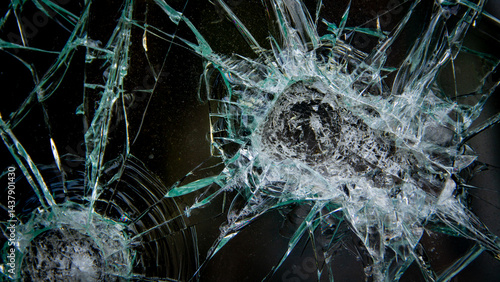 surface of broken glass with multiple impact points and diverging cracks.
