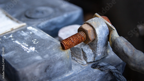 Car battery terminal with rusty bolt and attached cable.