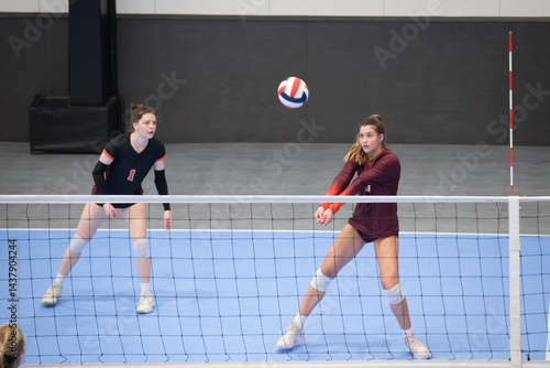 Female college volleyball player passing the ball while the libero watches