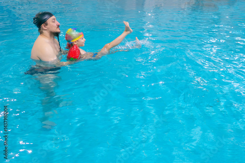 Obraz na płótnie Happy middle-aged father swimming with cute adorable baby in swimming pool. Smiling dad and little child, boy having fun together. Active family spending leisure and time in spa hotel. Concept of kids w salonie