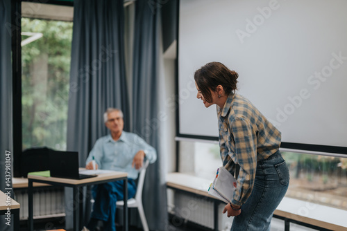A classroom scene featuring students interacting with an elderly professor, fostering a dynamic and educational environment. The image conveys learning, communication, and academic collaboration.