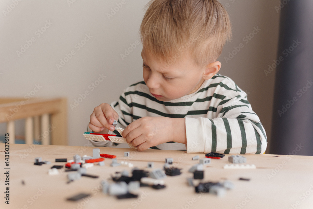 © Karabas - A 4-year-old white boy of European race plays a plastic construction kit sitting at a table. A boy is playing a plastic construction kit. close-up © Karabas - A 4-year-old white boy of European race plays a plastic construction kit sitting at a table. A boy is playing a plastic construction kit. close-up