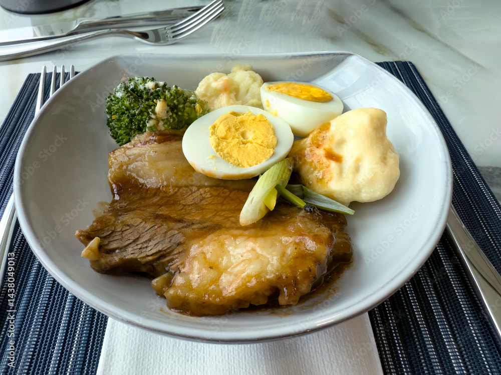 Close up view of roast beef in gravy with various vegetables and sliced egg