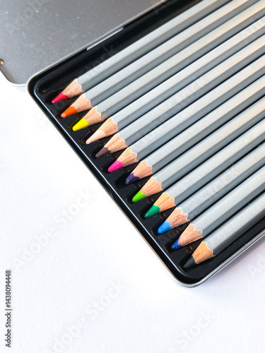 A set of pastel colored wooden pencils on a white sheet of watercolor paper for drawing.