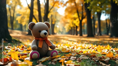 A teddy bear sitting on the ground surrounded by leaves