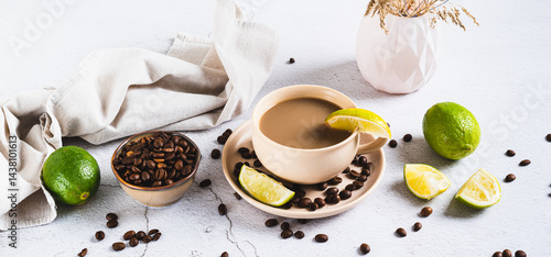 Cold coffee with lime wedges in a cup on the table web banner