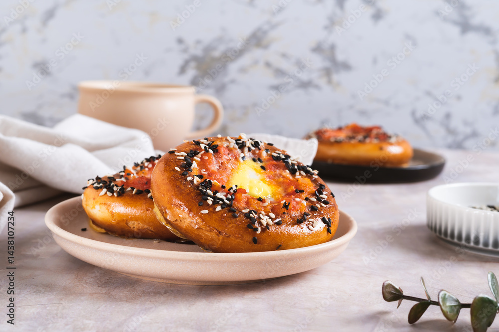 Baked bagels with tomato and quail egg on a plate on the table