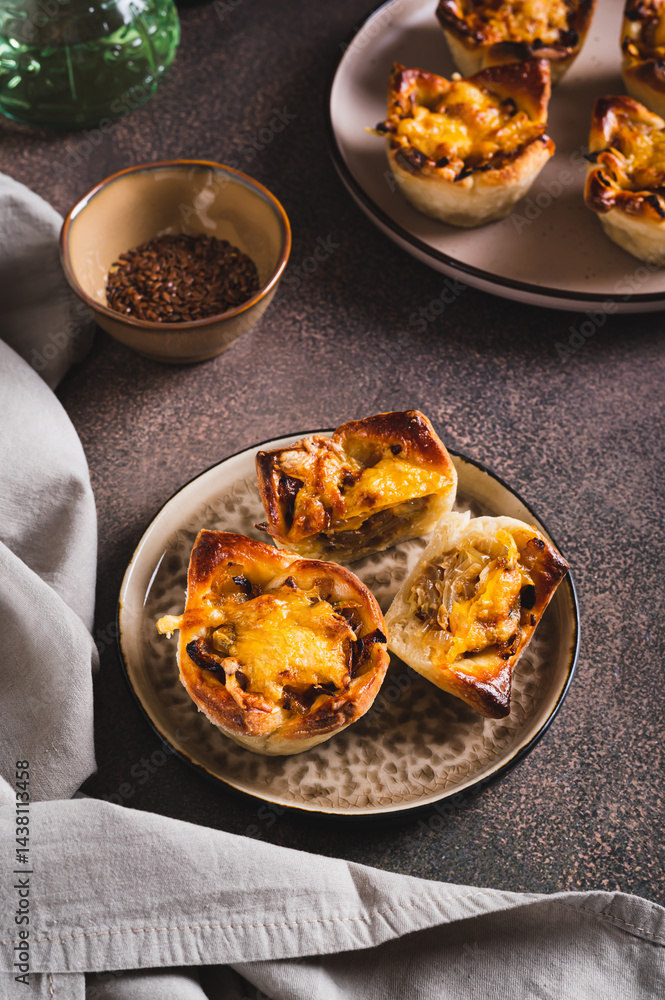 Homemade caramelized onion savory pies on a plate on the table vertical view