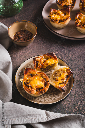 Homemade caramelized onion savory pies on a plate on the table vertical view