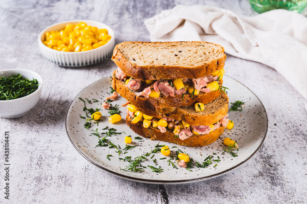 Tuna and corn salad on grain bread on a plate on a table