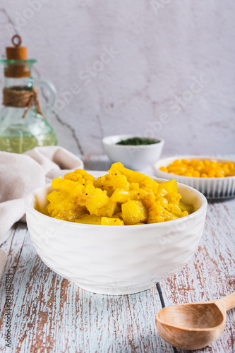 Obraz na płótnie Vegetarian curry with potatoes and cauliflower in a bowl on the table vertical view w salonie