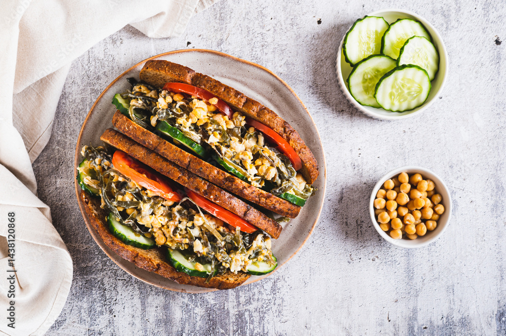 Vegetarian sandwich with seaweed, chickpeas, cucumber and tomato on grain bread top view