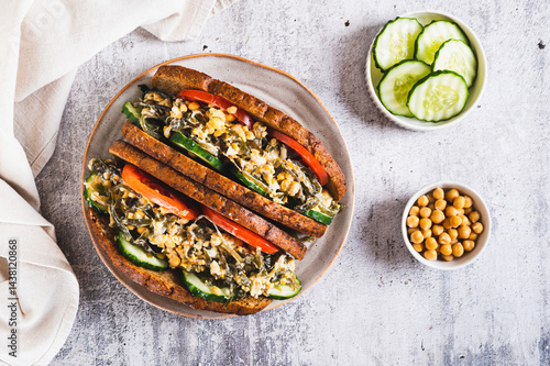 Vegetarian sandwich with seaweed, chickpeas, cucumber and tomato on grain bread top view