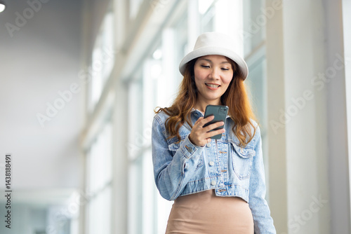 Obraz na płótnie Happy Female Travelling use smartphone. Happy asian woman passenger traveler waiting for departure with suitcase at modern airport terminal w salonie