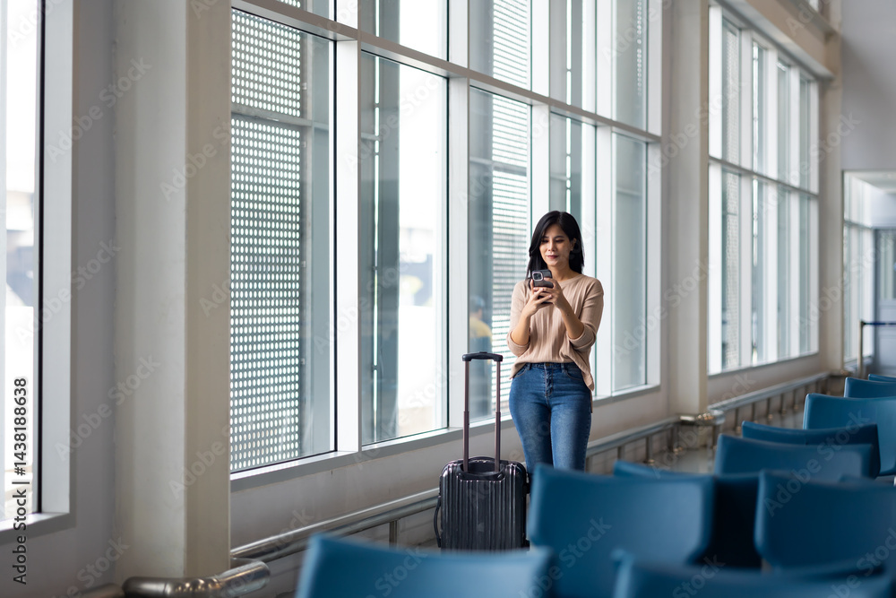 Happy Female Travelling use smartphone. Happy asian woman passenger traveler waiting for departure with suitcase at modern airport terminal