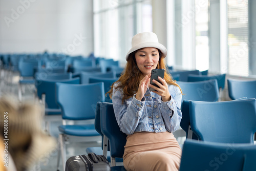 Obraz na płótnie Happy Asian Woman waiting for flight at airport lounge. Happy asian woman passenger traveler waiting for departure with suitcase at modern airport terminal w salonie